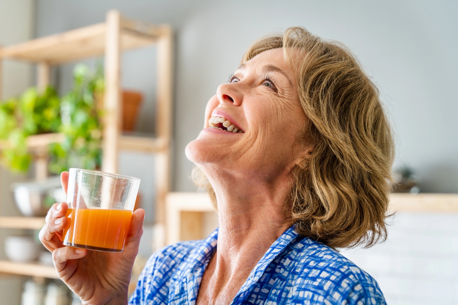 Happy midlife woman holding a glass of orange juice, symbolizing Vitamin C and immune support during menopause